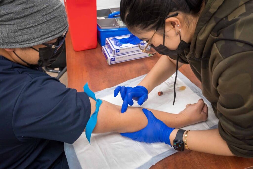 A Phlebotomy student practices finding a vein on a fellow student, as they prepare for their CPT-1 Certification.
