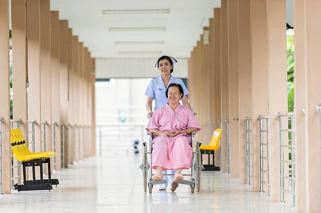 Picture of a healthcare worker with training and proficiency in both Nursing and Phlebotomy assisting her patient in a wheelchair.